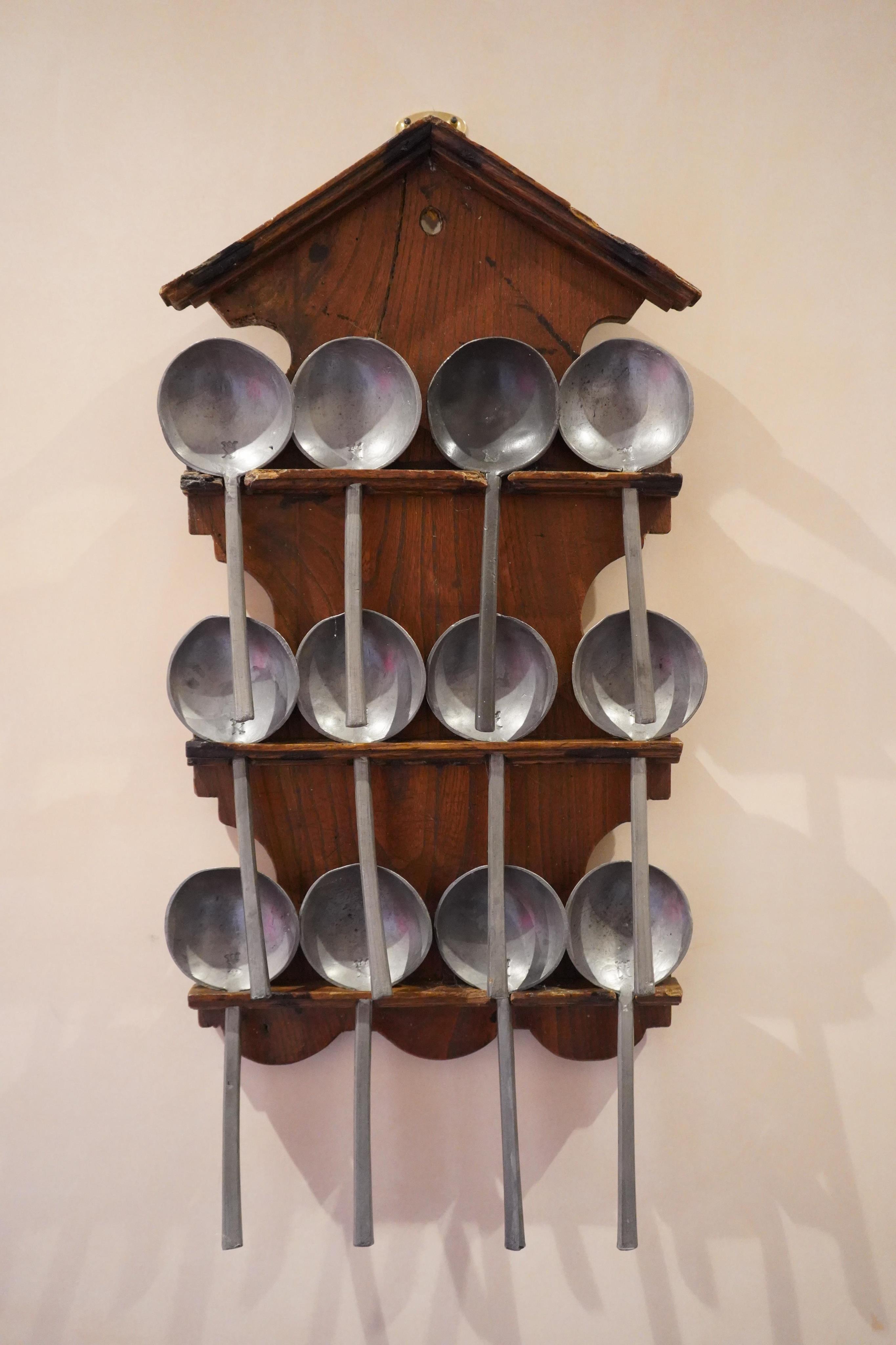 An 18th century Dutch Folk Art spoon rack with twelve English pewter spoons, 18th/19th century, 50cm high. Condition - some chipping to the wood